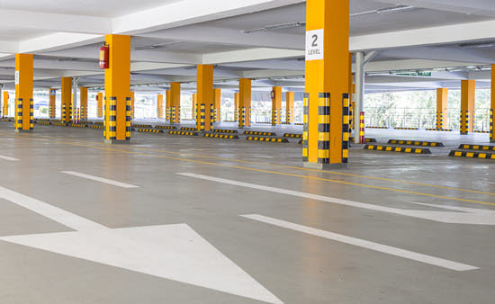 Clean parking garage with orange pillars and white arrows on deck