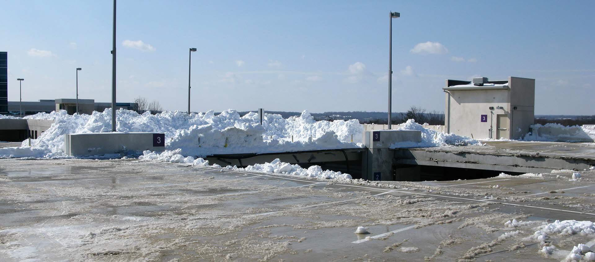 Snow piles and ice on the upper level of a parking structure
