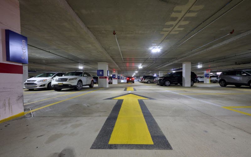 Clean parking garage with orange pillars and white arrows on deck